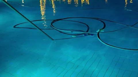Cleaning the pool bottom with a water vacuum cleaner in the evening. Stock Footage 326868968