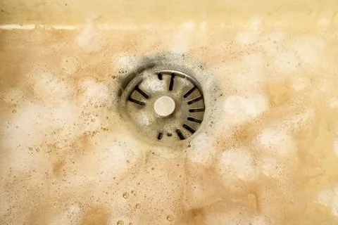 Cleaning process of a dirty kitchen sink with a metal drain using an alkali.. Stock Photos