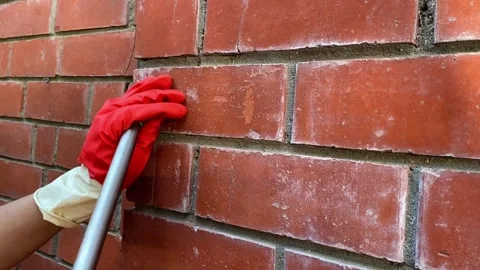 Cleaning a red brick wall from white outlets, a cleaning company is cleaning 库存影片 264343531