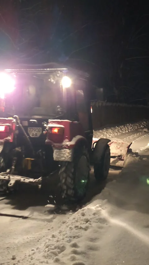 Cleaning the road in the winter park with a tractor in the evening Stock Footage 325674841