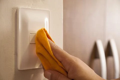 Cleaning the room light switch.. Stock Photos