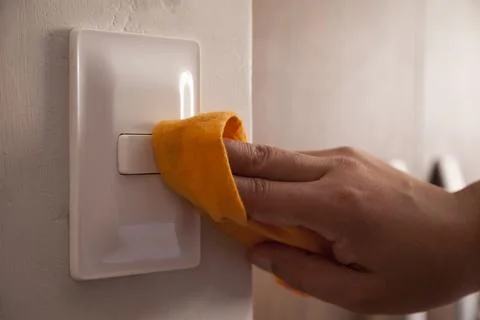 Cleaning the room light switch.. Stock Photos