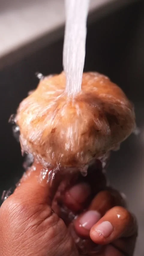 Cleaning a round object under running water in kitchen sink Video stock 330275320