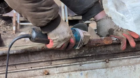 Cleaning rusty metal with a grinder, work at a construction site Stock Footage 306132865