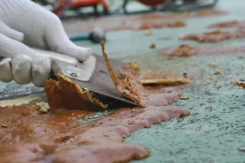 Cleaning with a scraper from excess hardened assembly foam on the concrete .. Stock Photos