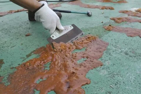 Cleaning with a scraper from excess hardened assembly foam on the concrete .. Stock Photos