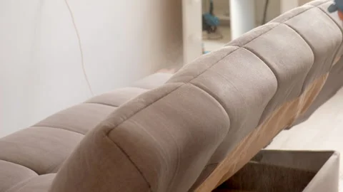 Cleaning service worker spraying foamy detergent on sofa to remove stains dirt. 스톡 동영상 311800799