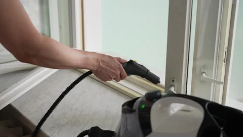 Cleaning service worker using steam cleaner washing window frame, close-up Stock Footage 310800712