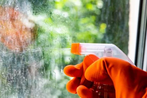 A cleaning service worker washes the window from dust and dirt on a dirty window Stock Photos