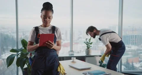 Cleaning services team. Young man using vacuum cleaner tidying office workspace Stock Footage 149263658