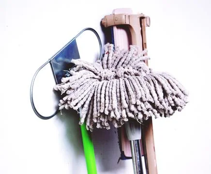 Cleaning set leaning on wall including mop, glass wipe and mop holder Stock Photos