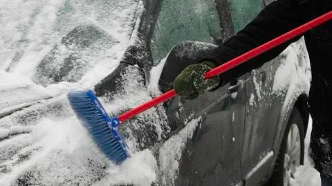 Cleaning the side of the car from the snow using the brush. Foto stock