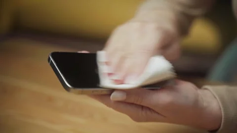 Cleaning a smartphone screen for better visibility and hygiene in a cozy indoor 스톡 동영상 303768653