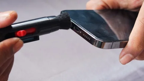 Cleaning a smartphone speaker grille with a small cleaning brush Stock Footage 343512343