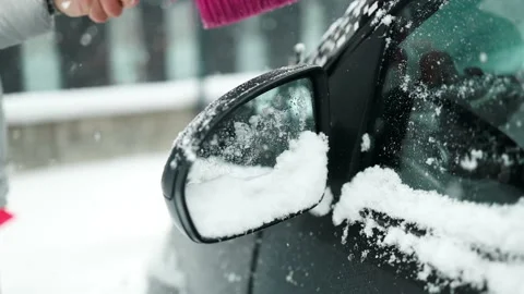 Cleaning snow from windshield. Cleaning and clearing the car from snow on a Stock Footage 297704814