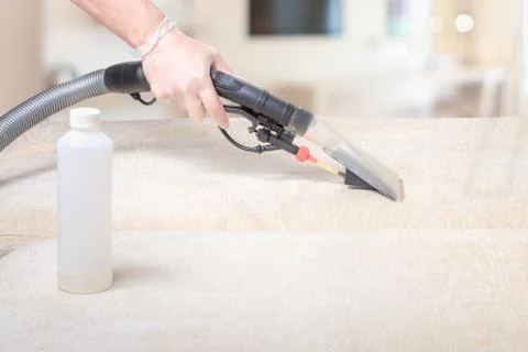 Cleaning the sofa with a vacuum cleaner, selective focus, cleaning fluid Stock Photos