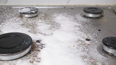 Cleaning spray being applied to a dirty gas stove surface with foam forming Stock Footage 318923924