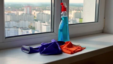 Cleaning spray bottle, cloth, and gloves placed on a windowsill with a pano.. Video stock 314609294