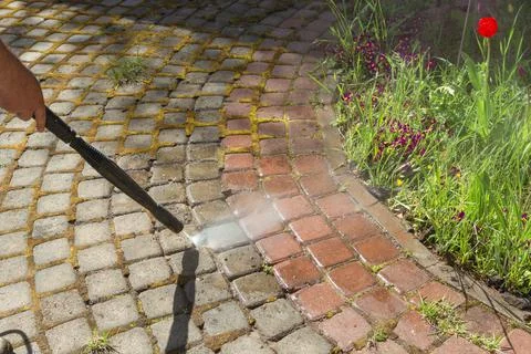 Cleaning street with high pressure power washer, washing stone garden paths Stock Photos
