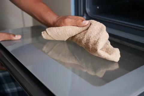 Cleaning the surface of a microwave with a cloth Stock Photos