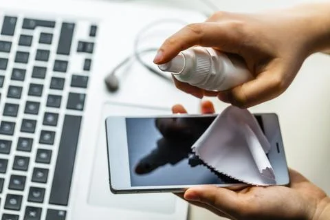 Cleaning the surface of the tablet. Hygiene to stop spreading coronavirus. Stock Photos