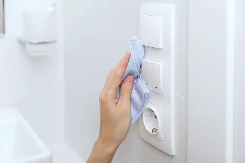 Cleaning switches and sockets with a microfiber cloth. Woman hand using wet wipe Stock Photos