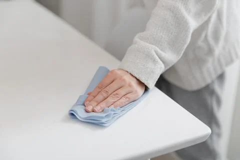 Cleaning the table with a blue microfiber cloth. Sanitize surfaces prevention in Stock Photos
