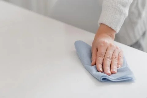 Cleaning the table with a blue microfiber cloth. Sanitize surfaces prevention in Stock Photos
