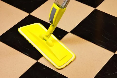 Cleaning of the tile floor surface from contamination with a cleaning mop. Stock Photos