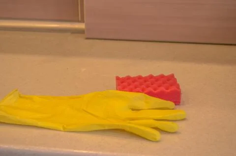 Cleaning tools in the kitchen rubber gloves and sponge lie on the dirty surfa Stock Photos