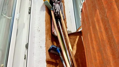 Cleaning Tools Stored Beside Window with Orange Curtain Indoors Vídeos de archivo 336839084