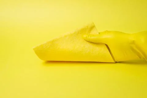 Cleaning tools on a yellow background. A gloved hand wipes with a rag.  Stock Photos