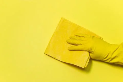 Cleaning tools on a yellow background. A gloved hand wipes with a rag.  Stock Photos