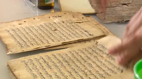 Cleaning the torn pages of an old book written in Arabic alphabet with brush Stock Footage 239328449