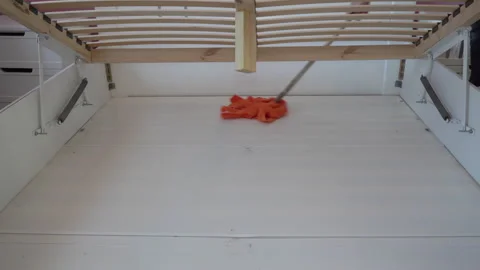 Cleaning under the bed with an orange mop Stock Footage 345407144