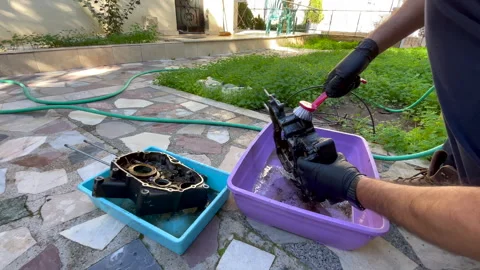 Cleaning very dirty engine crankcase parts on the ground outdoors with a brush Video stock 324840647
