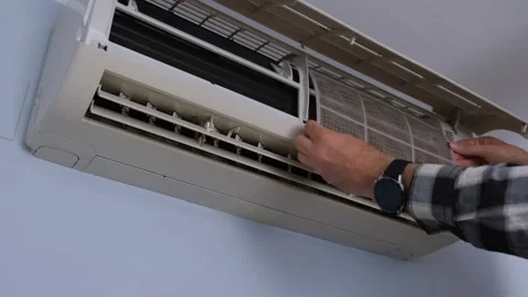 Cleaning wall air conditioner filter, hands in plaid shirt remove dirty mesh Stock Footage 326890134