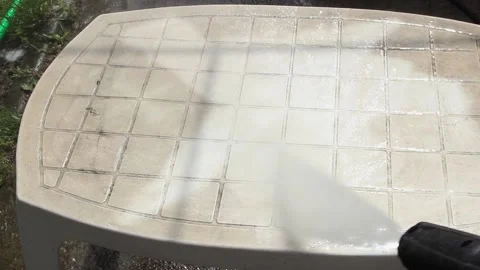 Cleaning a white plastic garden table with a high pressure water gun Stock Footage 149763440
