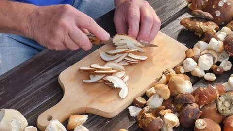 Cleaning of wild mushroom with kitchen knife in old hands. Man hands take carefu Stock Footage
