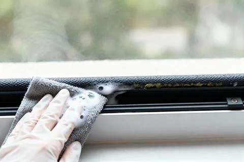 Cleaning a window frame with a soapy cloth for a fresh and tidy home Stock Photos