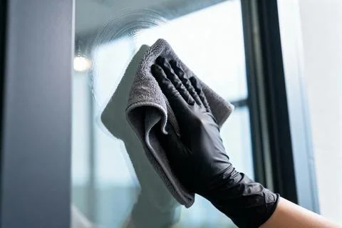 Cleaning a window with a microfiber cloth and black gloves Stock Photos