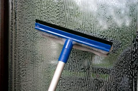 Cleaning window using a squilgee to wash glass. Stock Photos