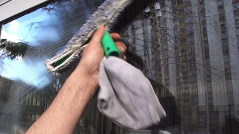 Cleaning the window. A young man cleans and polishes windows with a sponge Stock Footage 87418568