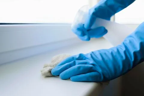 Cleaning windowsill surface with spray in protective gloves Stock Photos