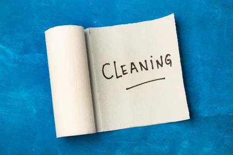 Cleaning word write on a paper kitchen napkin roll on a blue background Stock Photos