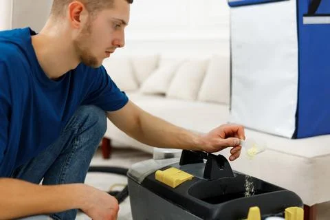 Cleaning worker in blue shirt adding chemicals in a cleaning vacuum Stock Photos