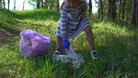 Cleaning the world. Save earth. The little girl collects garbage in the forest Stock Footage 196243136