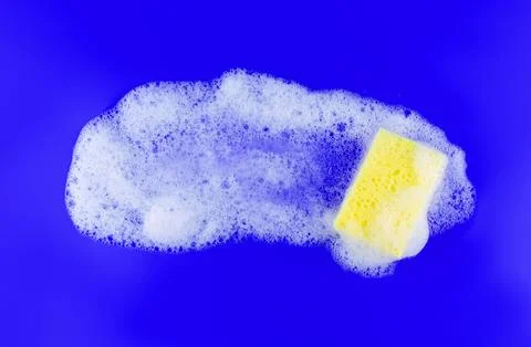 Cleaning yellow sponge and a soapy bubble foam on a blue background. Cleani.. Stock Photos