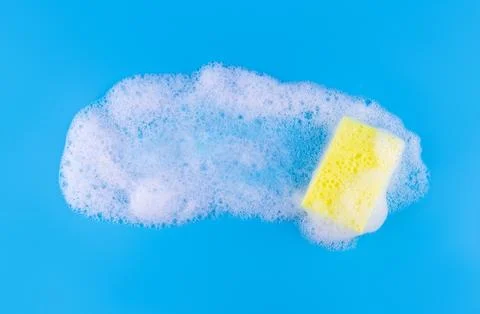 Cleaning yellow sponge and a soapy bubble foam on a blue background. Cleani.. Stock Photos