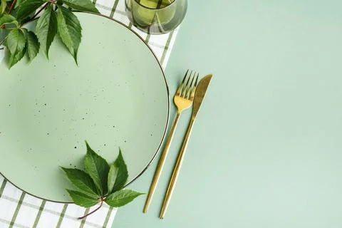 Cleanly set table with green plate and golden cutlery decorated with fresh .. Stock Photos